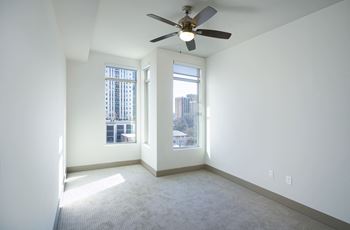 an empty living room with a ceiling fan and a window